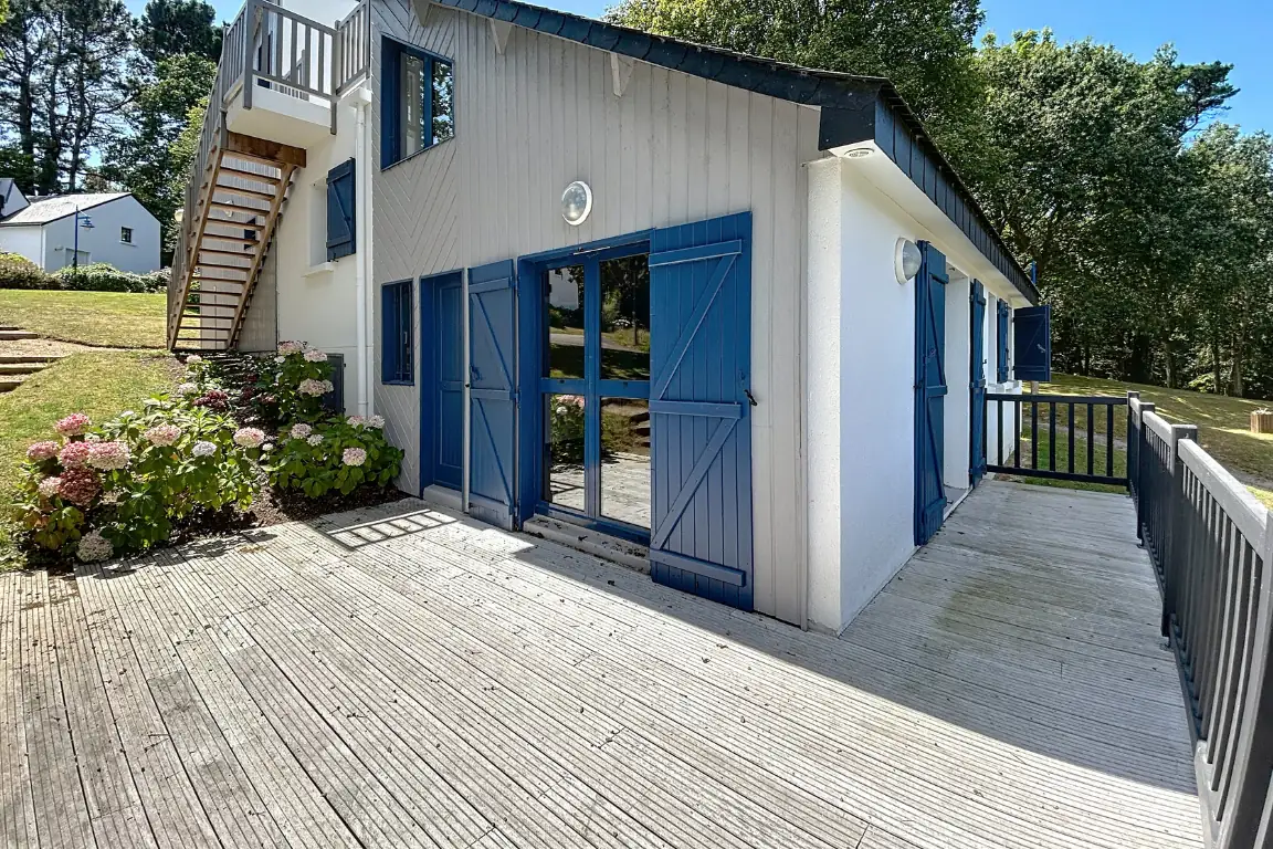Maison à volets bleus et large terrasse en bois